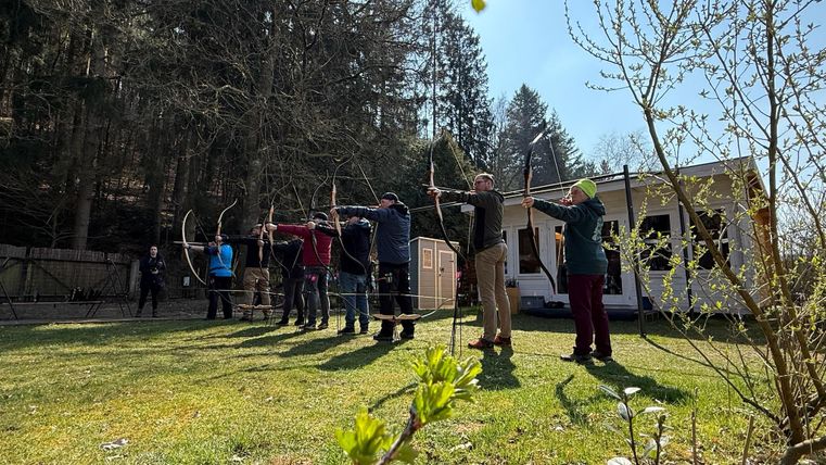 Ein Holztisch im Freien mit bunten Mosaik-Untersetzern und einer dekorativen Laterne. Dazu liegen eine Schere und einige Blumenelemente auf der Tischoberfläche.