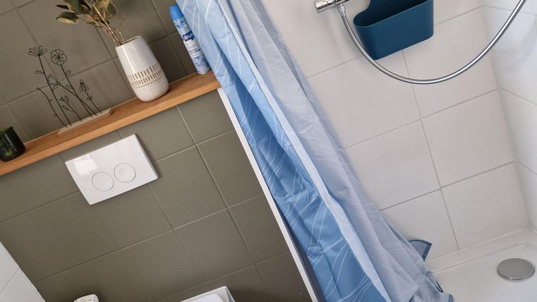 Ein modernes Badezimmer mit Duschbereich und wc. Die Wände sind hell, und es gibt eine Holzablage mit dekorativen Elementen.