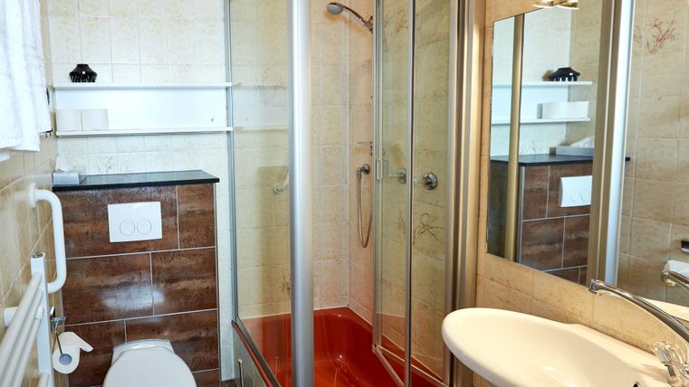 Ein modernes Badezimmer mit einer Dusche und einem Waschbecken. Es gibt einen Toilette und einen großen Spiegel.