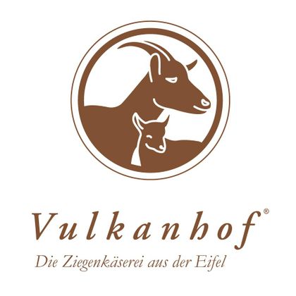 Ein Logo von Vulkanhof mit zwei Ziegen, einer großen und einer kleinen. Darunter steht "Die Ziegekäserie aus der Eifel".