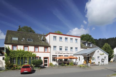 Ein gemütliches Gasthaus mit mehreren Gebäuden und einer einladenden Fassade. Es ist von einer schönen Umgebung umgeben und hat einen klaren blauen Himmel.