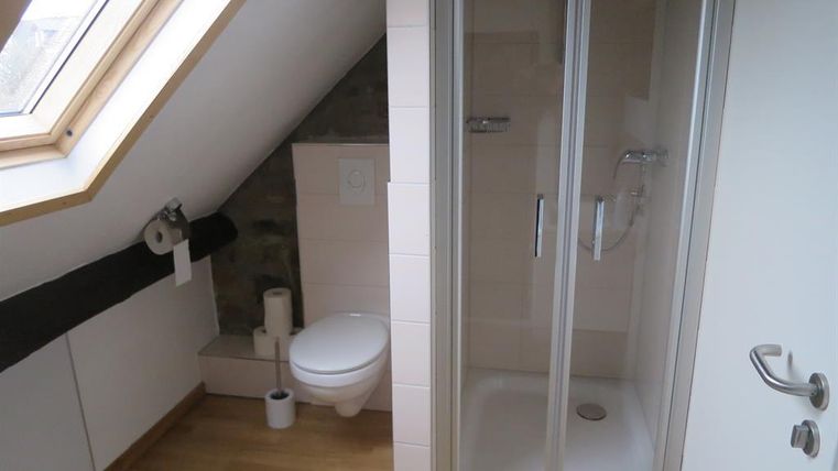 Ein modernes Badezimmer im Dachgeschoss mit Dusche und WC. Die Wände sind hell und die Böden aus Holz verleihen eine gemütliche Atmosphäre.