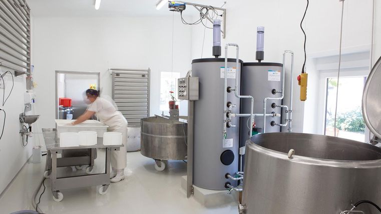 Eine moderne Produktionsstätte mit silbernen Tanks und einem Mitarbeiter, der arbeitet. Die Umgebung ist sauber und gut beleuchtet.