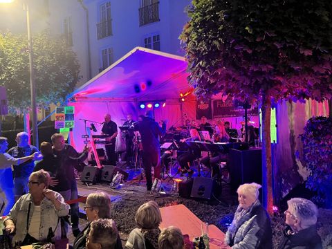 A musical performance under a tent with colorful lights.
People enjoy the atmosphere and dance in the night.