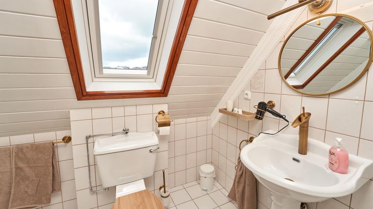 Ein modernes Badezimmer mit Dachfenster und elegantem Design. Es verfügt über eine Toilette, ein Waschbecken und dekorative Elemente.