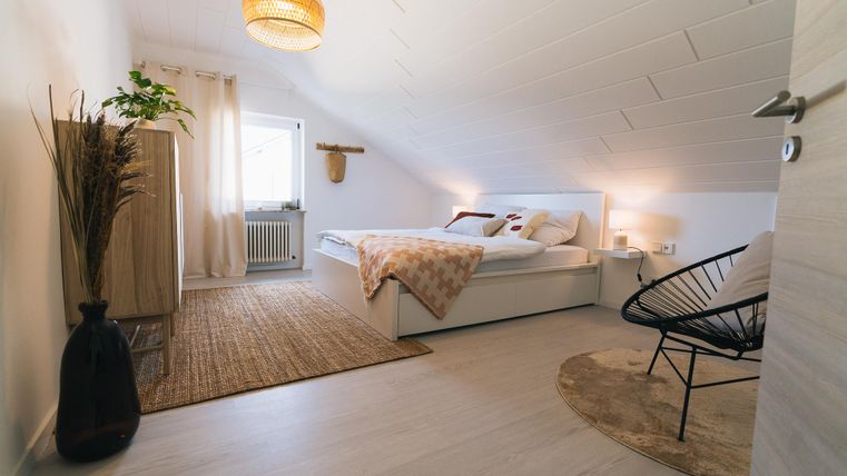 Ein gemütliches Schlafzimmer mit einem Doppelbett, einer großen Fensterfront und einer stilvollen Inneneinrichtung. Der Raum ist hell und freundlich, mit einer modernen Dekoration und viel Platz.