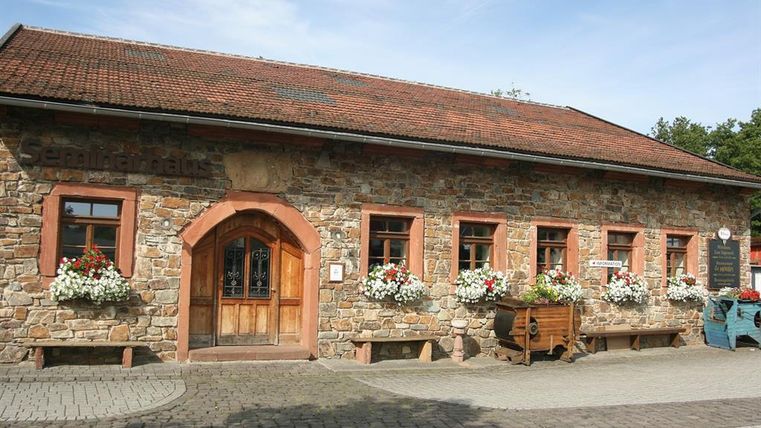 Ein eingeschossiges längliches Gebäude aus Bruchsteinen und mit einem rotem Ziegeldach. Der linksgelegene Eingang hat einen Rundbogen aus rötlichem Sandstein.Die Holztür ist im oberen Bereich aus Glas und mit einem Schmiedegitter verziert. Rechts und links sind 2 feststehene Holzelemente. Links des Einganges gibt es 1 Fenster, rechts davon fünf, vierreckige Sprossenfenster, die ebenfalls von Sandsteinen umrahmt sind. Vor den Fenstern sind Blumenkästen mit weißen und roten Blumen. Der Hof vor dem Gebäude ist gepflastert.