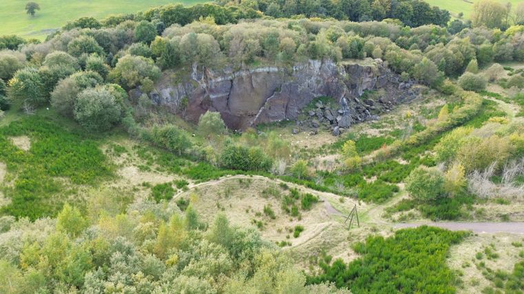 Luftaufnahme des bewaldeten Gebiets mit Felswand des Steffelberges und grünen Wiesen.