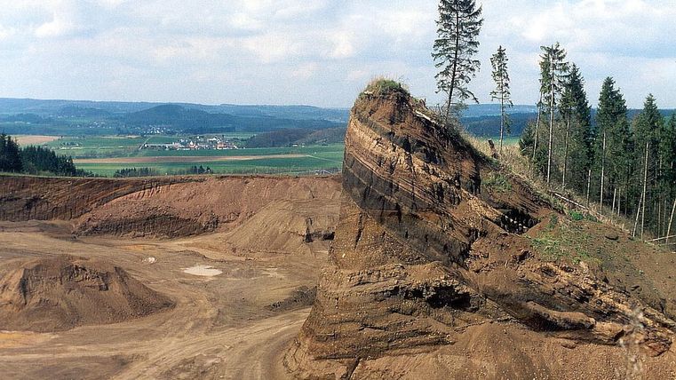 <p>Steinbruch Rockeskyller Kopf mit markanten Felsen und Bäumen, umgeben von weiter Landschaft und Feldern.</p>