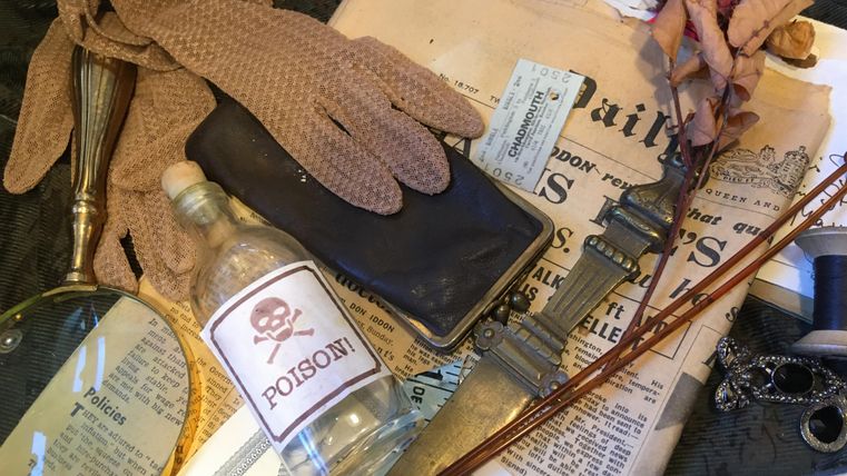 Tatortszene mit Giftflasche, Handschuhen, Lupe, Dolch, Zeitung und getrockneter Rose auf einem Tisch arrangiert.