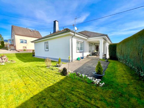 Ein modernes, weißes Haus mit einem gepflegten Garten. Die grüne Rasenfläche und die Bepflanzung schaffen eine einladende Atmosphäre.
