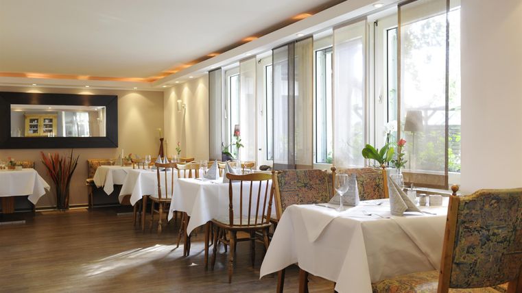Ein gemütliches Restaurant mit gedeckten Tischen und großen Fenstern. Die Atmosphäre ist hell und einladend.
