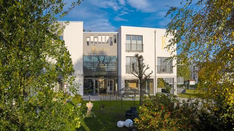 Ein modernes Gebäude mit großen Fenstern und einem klaren, blauen Himmel. Die umgebende Landschaft ist grün und einladend.
