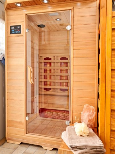 Eine moderne Sauna aus Holz mit einer Glasfront. Handtücher und ein Salzstein liegen bereit.