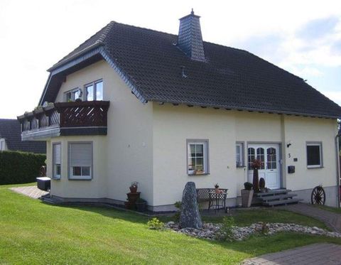 Ein schönes Wohnhaus mit einer hellen Fassade und einem schrägen Dach. Der Garten ist gepflegt und mit Steinen und Pflanzen geschmückt.