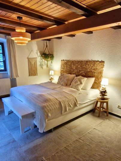 Ein gemütliches Schlafzimmer mit einem großen Bett und Holzdecke. Das Zimmer ist warm und einladend, mit einer ruhigen Farbpalette und stimmungsvoller Beleuchtung.