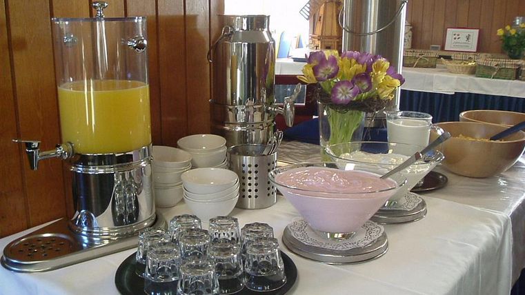 Ein Buffet mit verschiedenen Getränken und Speisen. Es gibt Saft, Joghurt und eine Auswahl an Schalen und Gläsern.