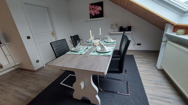 Ein moderner Essbereich mit einem Tisch und schwarzen Stühlen. Der Raum hat eine gemütliche Atmosphäre mit viel Tageslicht und einer dezenten Dekoration.