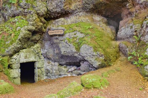 Grotto-ingang in mos bedekte rots, bord 'Zweedse vesting'. Natuurpad leidt naar de opening. Mystieke sfeer.