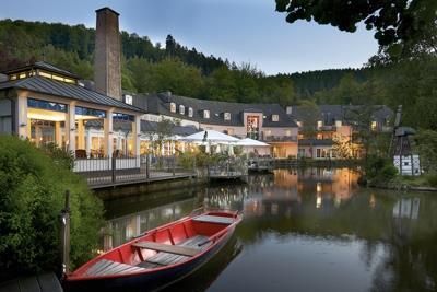 Ein hübsches Hotel am Wasser mit einer roten Boot. Die Umgebung ist grün und die Atmosphäre ist ruhig und einladend.