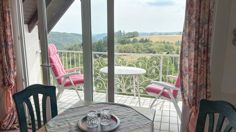 A cozy room with a view of the countryside. Two chairs are on the balcony, perfect for relaxing.