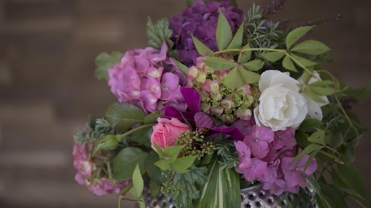 Ein schöner Blumenstrauß mit rosa, lila und weißen Blüten. Die Blumen sind in einer silbernen Vase angeordnet und ergänzen sich harmonisch.
