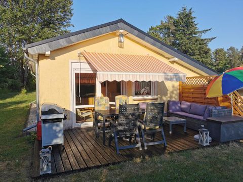 Ein gemütliches Haus mit einer Terrasse und Sitzmöglichkeiten im Freien. Die bunte Markise spendet Schatten und lädt zum Entspannen ein.