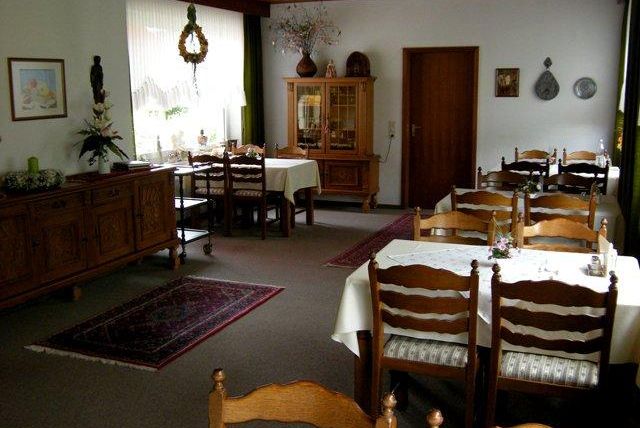 Ein gemütliches Restaurant mit Holzmöbeln und idyllischer Atmosphäre. Die Tische sind schön gedeckt und von einem warmen Licht umgeben.
