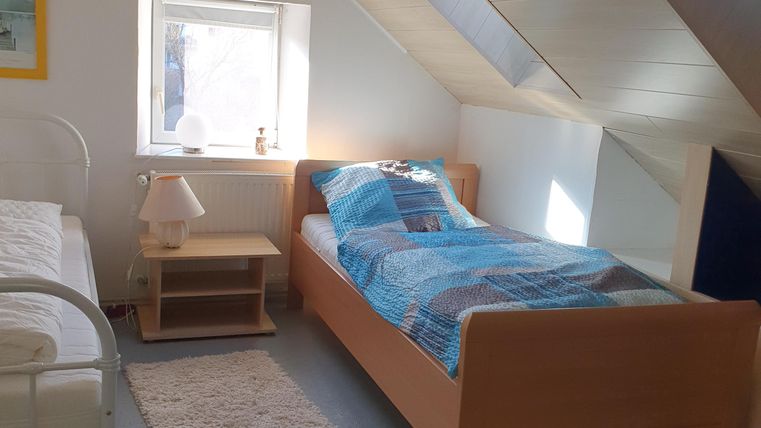 Ein helles Schlafzimmer mit zwei Betten und einer ruhigen Atmosphäre. Ein Fenster sorgt für natürliches Licht und die Einrichtung ist einfach und funktional.