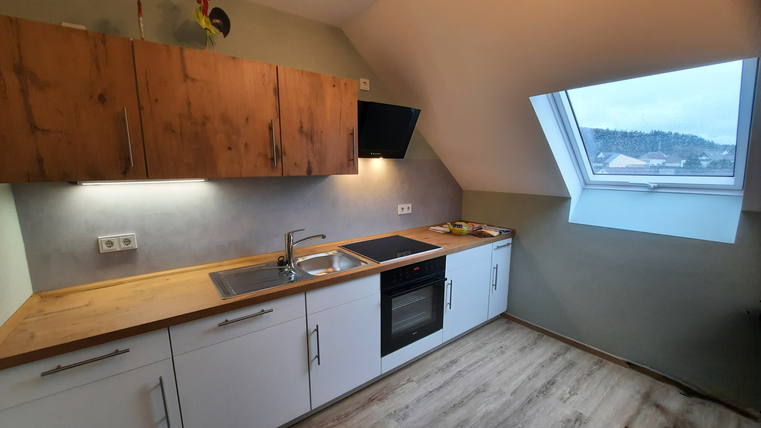 Eine moderne Küche mit Holz- und weißen Möbeln. Das Fenster bietet einen Blick auf die Landschaft.