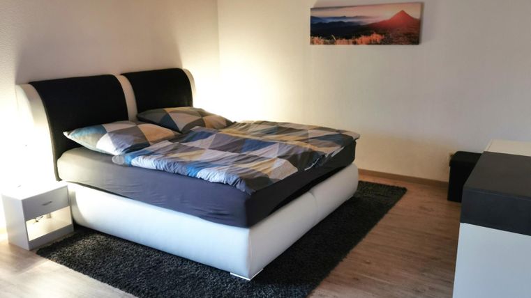 Ein modernes Schlafzimmer mit einem Doppelbett und bunten Bettwäsche. Das Zimmer hat einen gemütlichen Teppich und eine ruhige Atmosphäre.