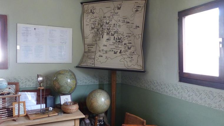 Ein Raum mit einem großen historischen Kartenausschnitt an der Wand. Auf einem Tisch stehen verschiedene Globusse und historische Gegenstände.