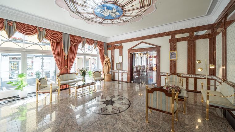 Ein eleganter Lobbybereich mit einem marmornen Boden und reich verzierten Fenstern. Die geschmackvolle Einrichtung und die Kunstwerke verleihen ihm einen luxuriösen Charme.