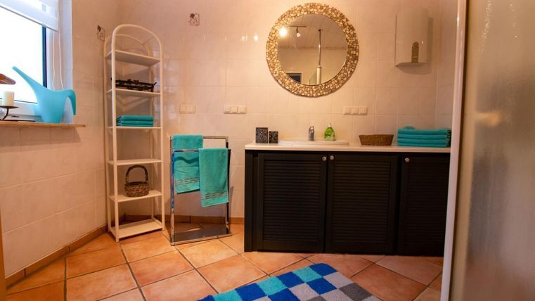 Ein modernes Badezimmer mit einem großen Spiegel und eleganten Handtüchern in blau. Der Raum ist hell und ordentlich mit einer stilvollen Regal und Fliesenboden.