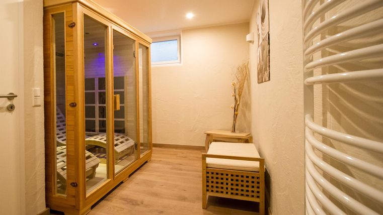 Ein gemütlicher Wellnessbereich mit einer Sauna und einem kleinen Platz zum Entspannen. Die Wände sind hell, und das Licht schafft eine beruhigende Atmosphäre.