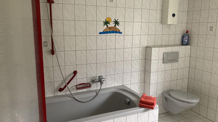 Ein modernes Badezimmer mit einer Badewanne und einer Dusche. Die Wände sind gefliest und es gibt einen Toilettenbereich.