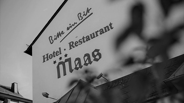 Ein Blick auf die Fassade eines Hotels und Restaurants mit dem Namen „Maas“. Die Schrift ist markant und einladend.