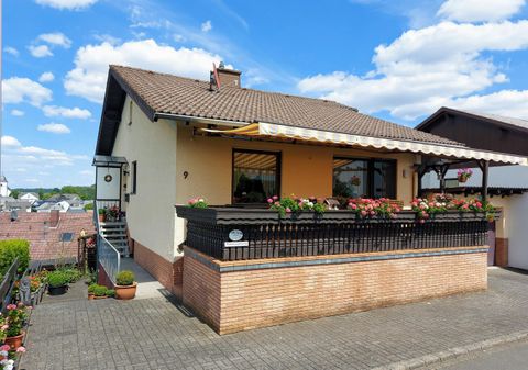 Ein schönes Haus mit einem Balkon und Blumenkästen. Der Himmel ist blau mit einigen Wolken.