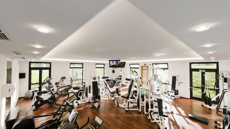 Ein modernes Fitnessstudio mit verschiedenen Trainingsgeräten und großen Fenstern. Der Raum ist hell und geräumig, ideal für Sport und Fitness.