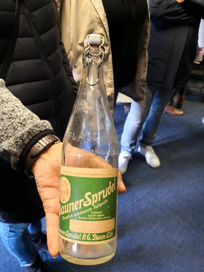 Eine Flasche mit Mineralwasser namens "Gunner Sprudel". Die Flasche ist in der Hand einer Person gehalten und hat ein klassisches Design.