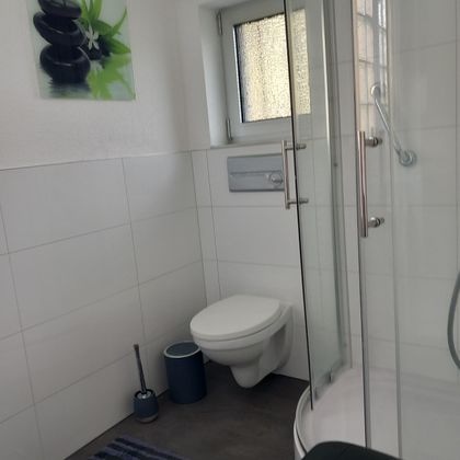 A modern bathroom with a shower and a toilet.
Bright tiles and a minimalist design create a clean atmosphere.
