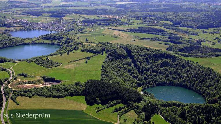 Eine malerische Landschaft mit mehreren Seen und üppigen grünen Wäldern. Die Gegend ist von sanften Hügeln umgeben und bietet eine ruhige, natürliche Atmosphäre.