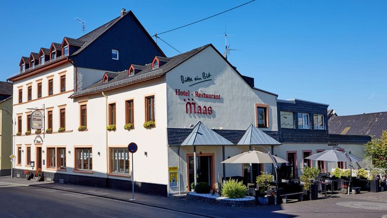 Ein charmantes Hotel mit einem Restaurant an der Straßenfront. Es hat eine helle Fassade und eine einladende Terrasse.