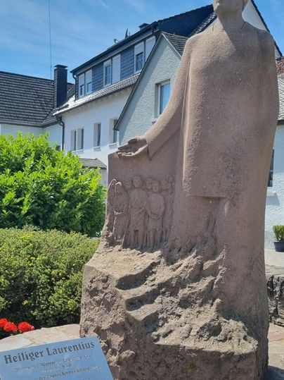 Ein großer Felsbrocken steht neben einem Radweg in einer ruhigen Umgebung. Ein Fahrrad steht in der Nähe des Felsens.