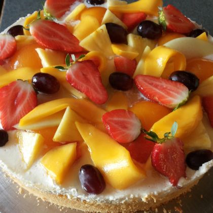Ein leckerer Obstkuchen mit frischen Früchten wie Mangos, Erdbeeren und Trauben. Die bunte Dekoration macht ihn besonders appetitlich.