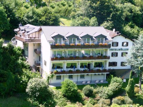 Ein schönes Hotel mit Balkonen und blühenden Pflanzen. Die Anlage liegt umgeben von grüner Natur und bietet einen einladenden Anblick.