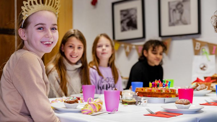 Ein fröhliches Geburtstagsfeier mit mehreren Mädchen am Tisch. Der Tisch ist mit Kuchen und bunten Getränken dekoriert.