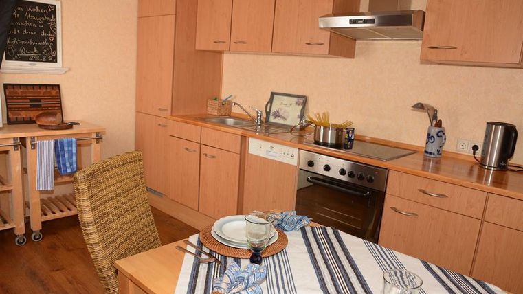 Eine moderne Küche mit Holzschränken und Geräten. Der Tisch ist eingedeckt mit Geschirr und Besteck.