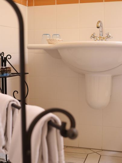 Ein Badezimmer mit einem Waschbecken und einem Handtuchhalter. Die Wände sind weiß gefliest und der Raum wirkt hell und einladend.