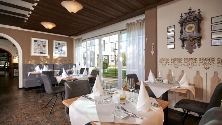 Ein gemütliches Restaurant mit eleganten Tischgedecken und einer einladenden Atmosphäre. Große Fenster bieten einen Blick auf die Außenanlage.